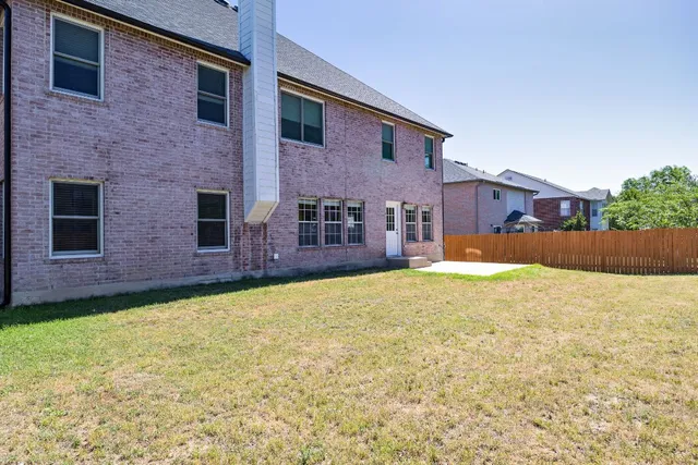 a backyard of a house with yard and wooden fence
