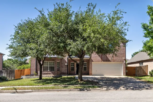 a front view of a house with a tree