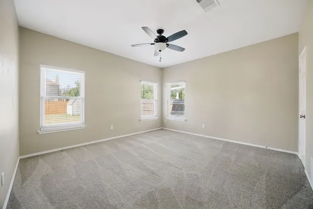 an empty room with window and ceiling fan