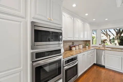 a kitchen with granite countertop white cabinets and appliances