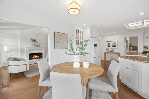 a view of a dining room with furniture a fireplace and wooden floor