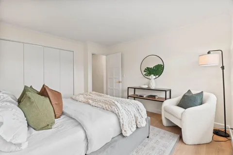 a bedroom with a bed a couch and a lamp on dresser