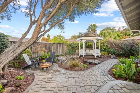 a view of a patio with table and chairs potted plants and large tree