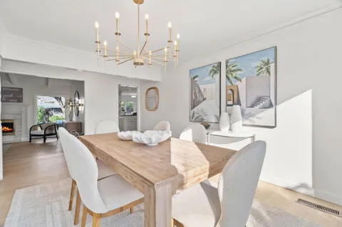a dining room with wooden floor a chandelier a wooden table and chairs