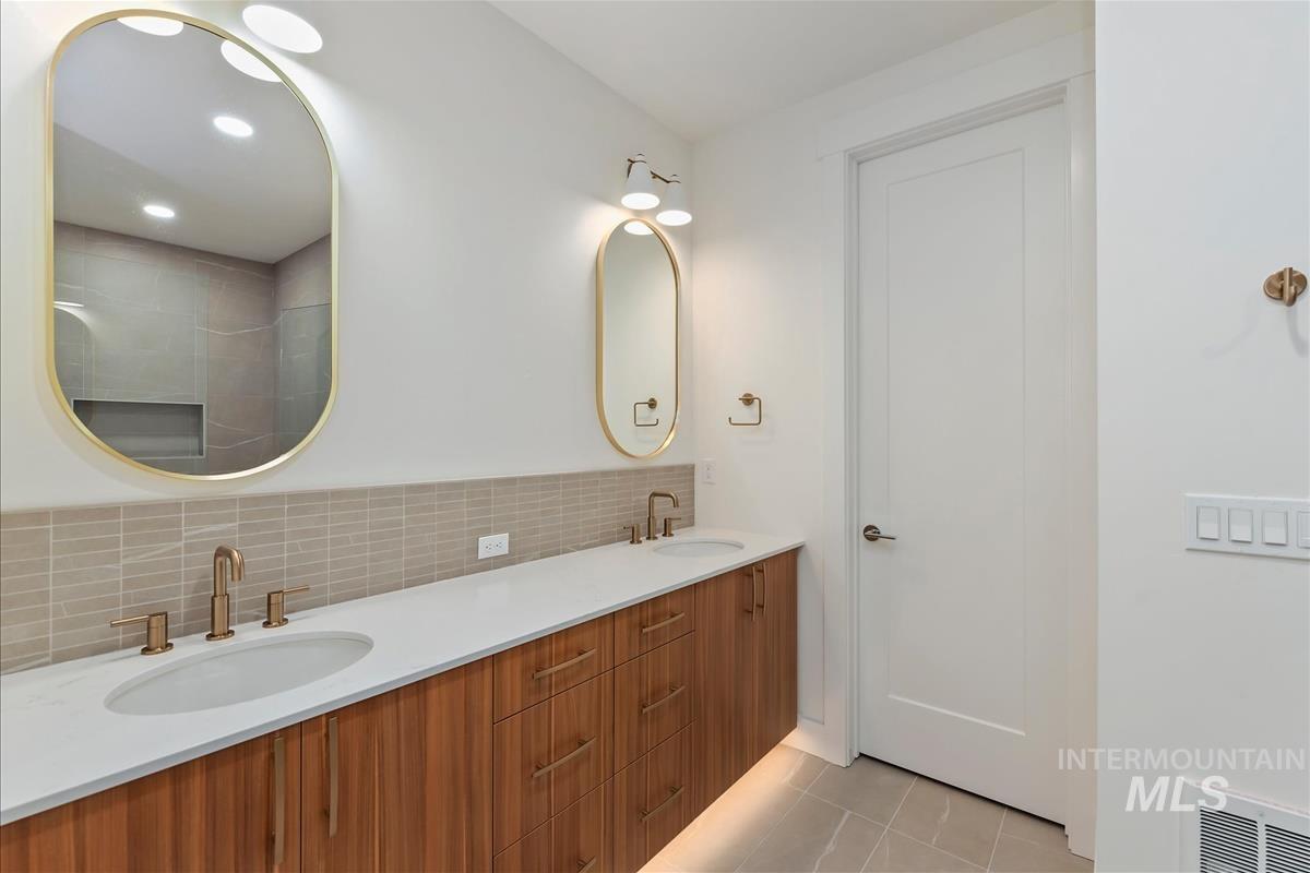 3213 West Moore Street Boise, ID 83702 - Photo 20 of 32 Dual oval mirrors with gold-tone frames above a wood-finish double vanity