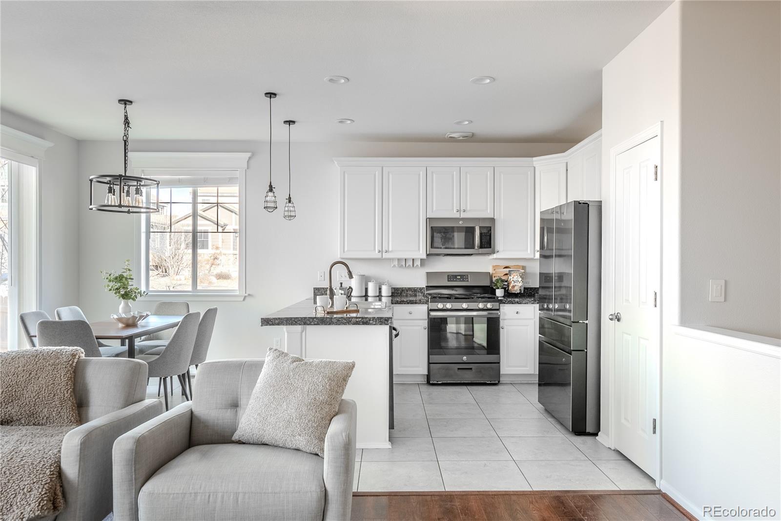 602 Mathews Way Erie, CO 80516 - Photo 15 of 50 a living room with stainless steel appliances kitchen island granite countertop a refrigerator a stove a sink dishwasher and white cabinets with wooden floor
