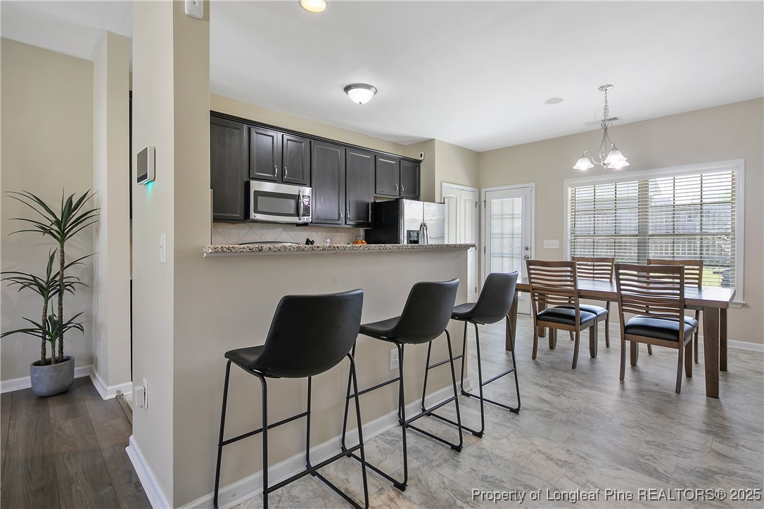 21 Bicentennial Way Cameron, NC 28326 - Photo 11 of 50 a kitchen with stainless steel appliances granite countertop a stove top oven a sink a dining table and chairs with wooden floor