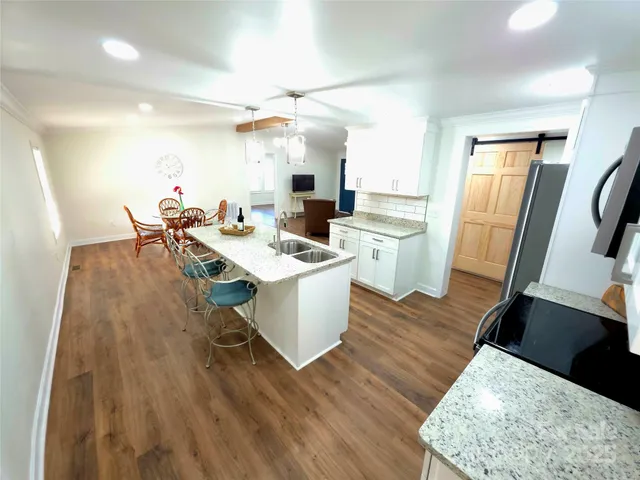 a living room with stainless steel appliances furniture a dining table and kitchen view