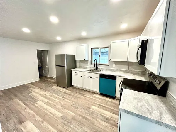 a kitchen with stainless steel appliances kitchen island granite countertop a refrigerator a stove a sink dishwasher and a refrigerator with wooden floor
