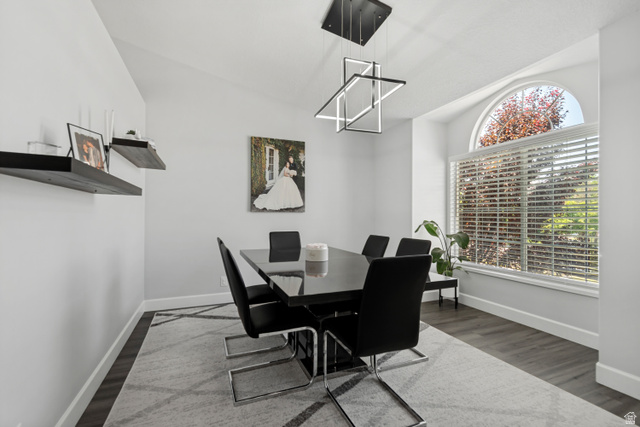 4752 South 4075th Street West Roy, UT 84067 - Photo 4 of 28 Dining space featuring a large arched window, vaulted ceiling, modern geometric chandelier, and wood-finish flooring