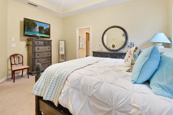 a bed sitting in a bedroom next to a window with a flat tv screen and dresser
