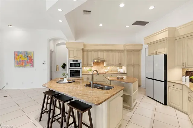 a kitchen with stainless steel appliances kitchen island granite countertop a dining table chairs and refrigerator