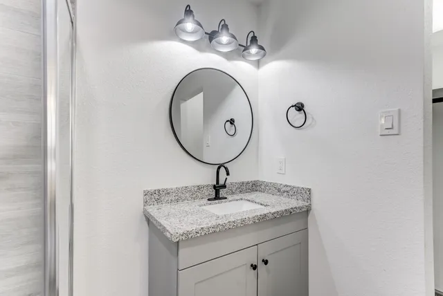 a bathroom with a granite countertop sink and a mirror