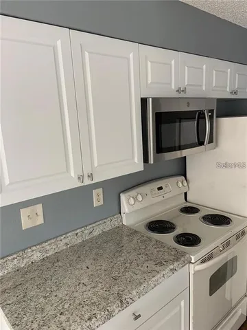 a kitchen with granite countertop a sink a stove and microwave