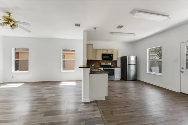 a kitchen with granite countertop a refrigerator and wooden floor