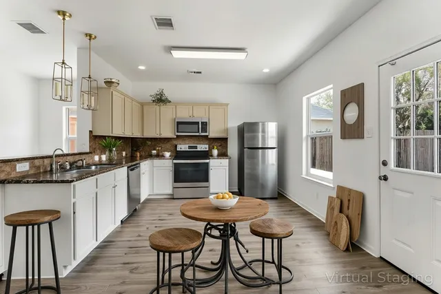 a kitchen with stainless steel appliances a refrigerator a stove a sink dishwasher and white cabinets with wooden floor