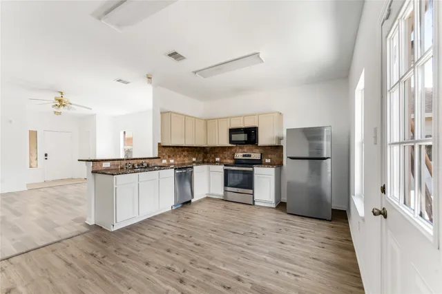 a kitchen with granite countertop a refrigerator and a stove top oven