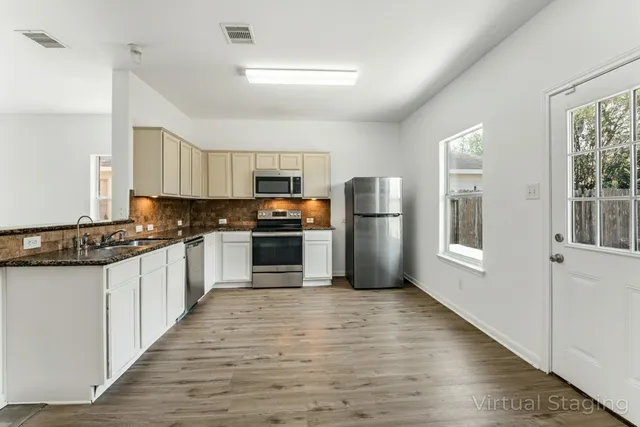 a large kitchen with cabinets wooden floor and stainless steel appliances
