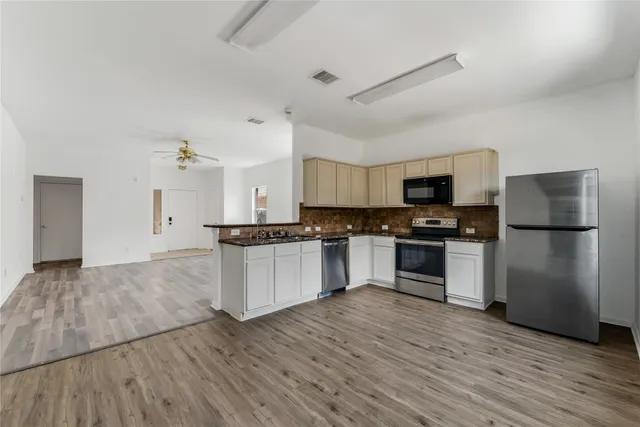 a kitchen with granite countertop a refrigerator and a stove top oven