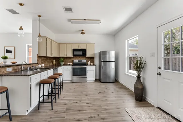 a kitchen with granite countertop a refrigerator a stove a sink a dining table and chairs