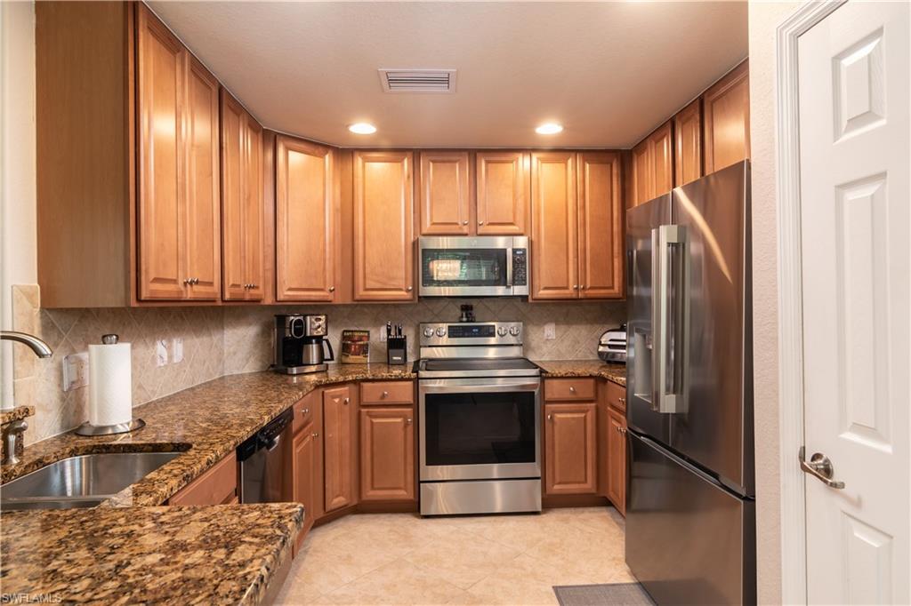 7878 Clemson Street, Unit 101 Naples, FL 34104 - Photo 6 of 18 a kitchen with stainless steel appliances granite countertop a stove sink and refrigerator