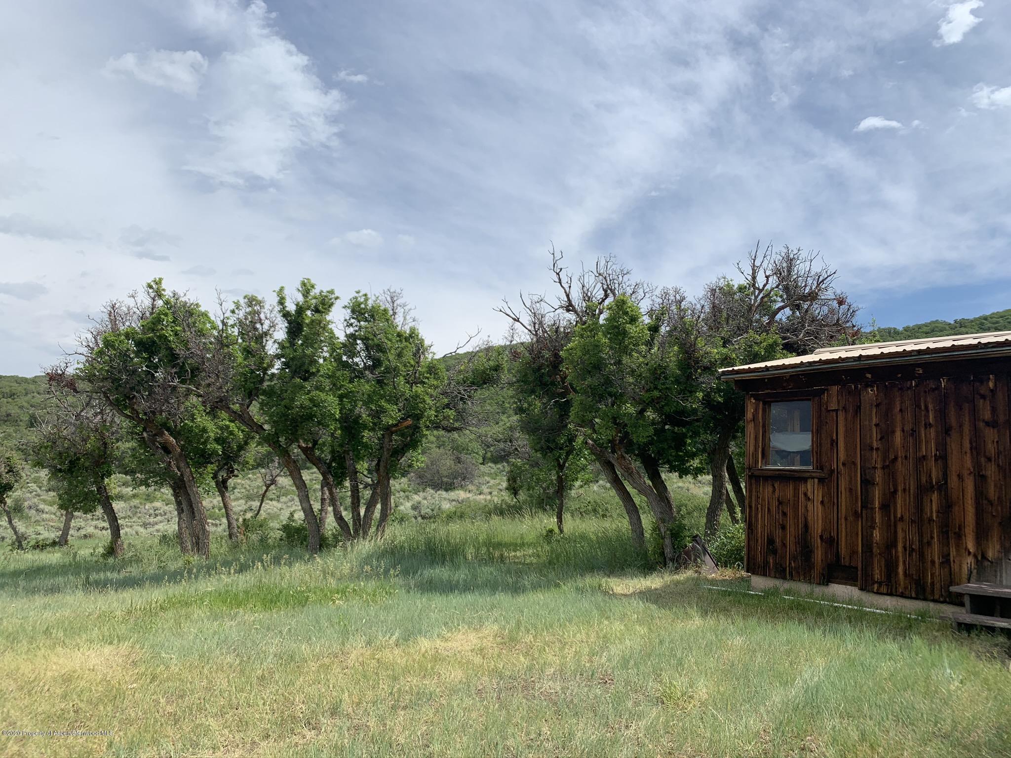 Tbd Wild Acres Ranch Road Rifle, CO 81650 - Photo 10 of 33 a backyard of a house with lots of green space and wooden fence