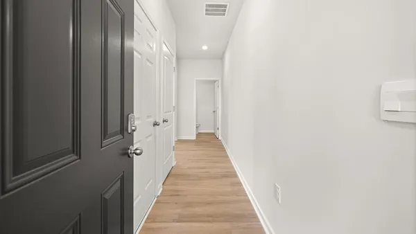 a view of a hallway with wooden floor and a bathroom