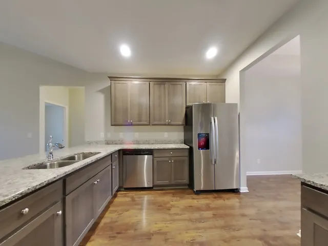 a kitchen with granite countertop stainless steel appliances a sink and a refrigerator