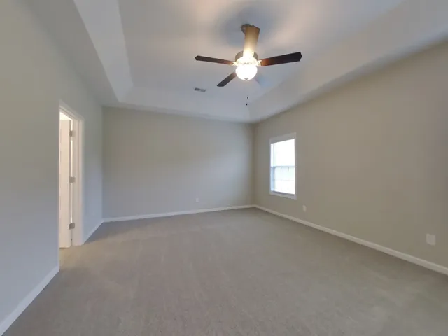an empty room with a chandelier fan and windows