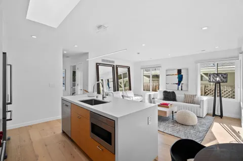 a kitchen with stainless steel appliances kitchen island granite countertop a stove a refrigerator a oven a dining table and chairs with wooden floor