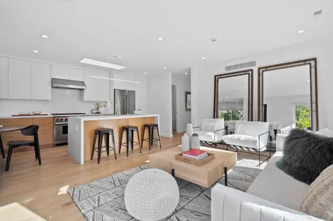 a living room with furniture kitchen view and a large window
