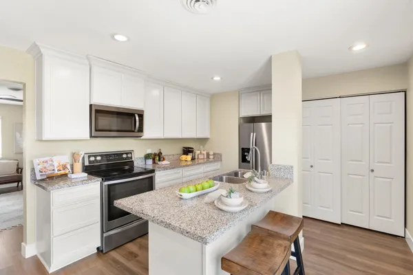 a kitchen with stainless steel appliances granite countertop a stove top oven a dining table and chairs with wooden floor