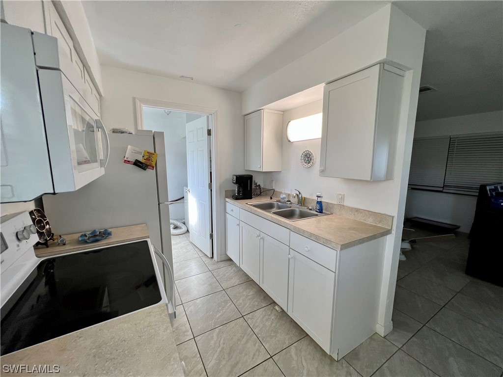 24 Alabama Road South Lehigh Acres, FL 33936 - Photo 6 of 17 a kitchen with a sink stove and cabinets