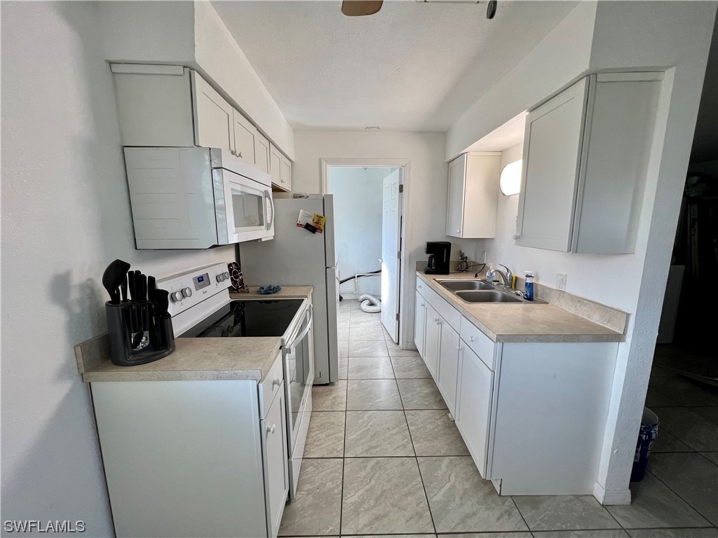 24 Alabama Road South Lehigh Acres, FL 33936 - Photo 7 of 17 a kitchen with a sink stove and cabinets