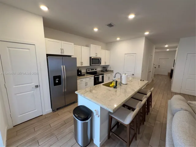 a kitchen with stainless steel appliances kitchen island granite countertop a sink a stove a dining table and chairs