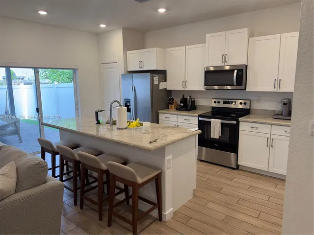 a kitchen with kitchen island a refrigerator stove microwave and cabinets
