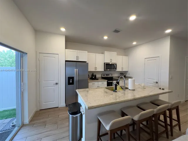 a kitchen with stainless steel appliances granite countertop a table chairs sink refrigerator and cabinets