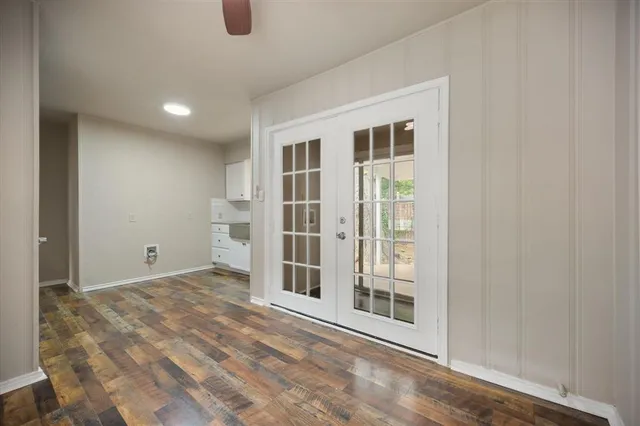a view of an empty room with wooden floor and windows