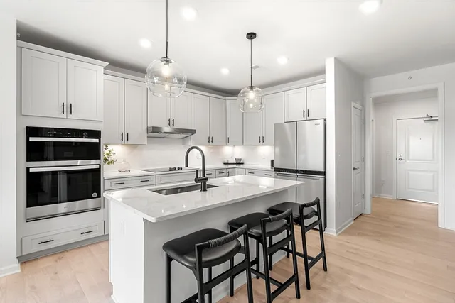 a kitchen with stainless steel appliances kitchen island a table chairs refrigerator and microwave