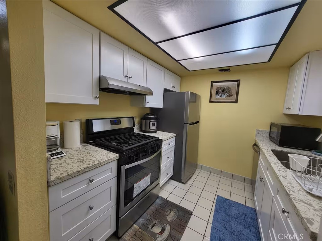 250 East San Jose Road, Unit 63 Palm Springs, CA 92264 - Photo 4 of 22 a kitchen with granite countertop wooden cabinets and a stove top oven