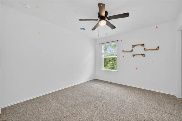 an empty room with ceiling fan and window