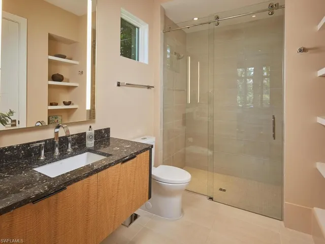 a bathroom with a granite countertop sink a toilet a mirror and shower