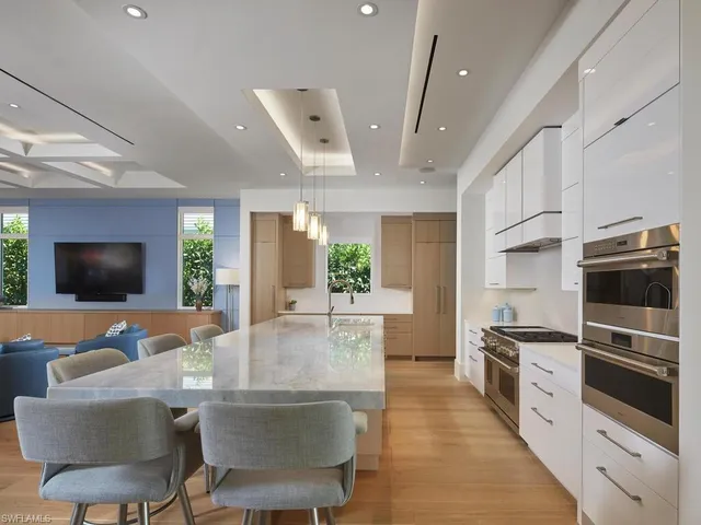 a living room with stainless steel appliances furniture a flat screen tv and a chandelier