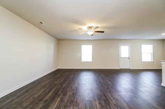 a view of an empty room with a window and wooden floor