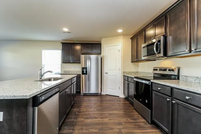a kitchen with stainless steel appliances granite countertop a stove a sink and a refrigerator