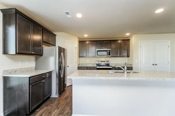 a kitchen with stainless steel appliances wooden cabinets a sink a stove a microwave and a refrigerator