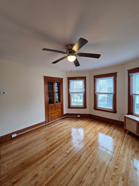 15 Berkmans Street, Unit 2 Worcester, MA 01602 - Photo 2 of 13 an empty room with wooden floor chandelier fan and windows