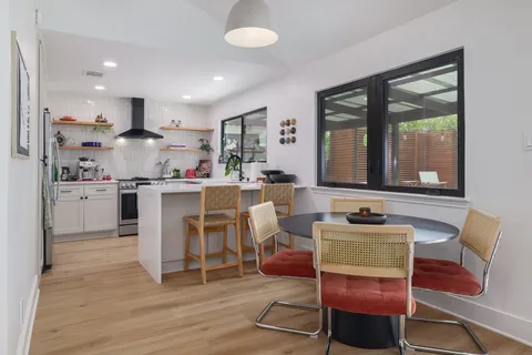 a living room with stainless steel appliances kitchen island granite countertop furniture a rug kitchen view and a large window