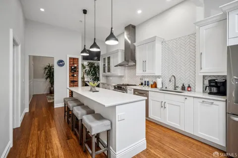 a kitchen with wooden floor and white cabinets