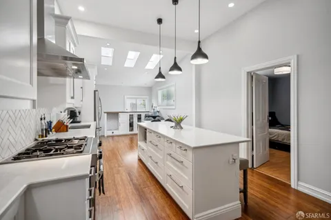 a large kitchen with kitchen island a stove a sink a center island and wooden floor